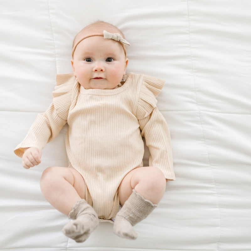 baby girl wearing our tan bodysuit